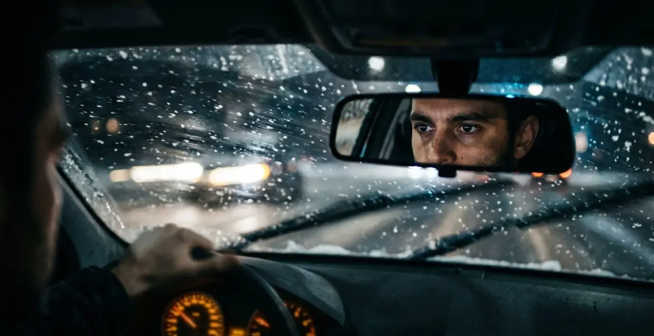Vue depuis l'habitacle d'une voiture la nuit montrant la technique de balayage visuel sur route enneigée